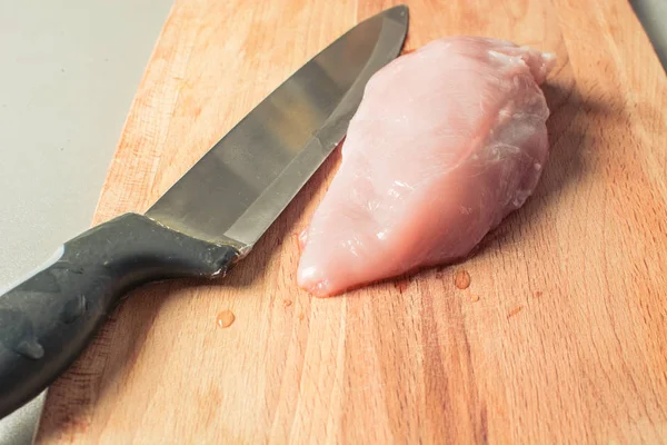 Raw chicken breast fillet with cutting knife on wooden board. — Stock Photo, Image