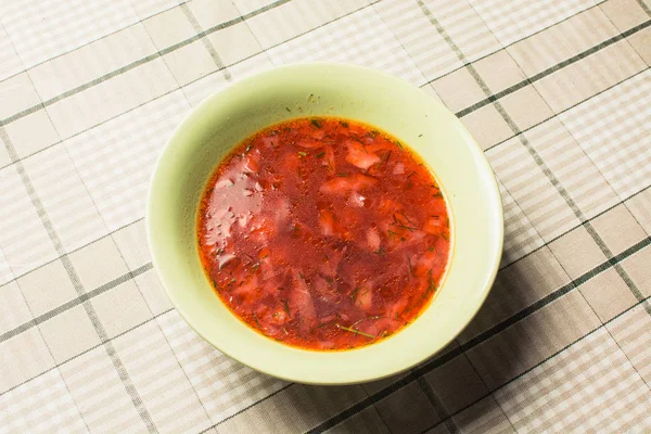 Rote Suppe Borschtsch in grünem Teller auf Küchentisch. — Stockfoto