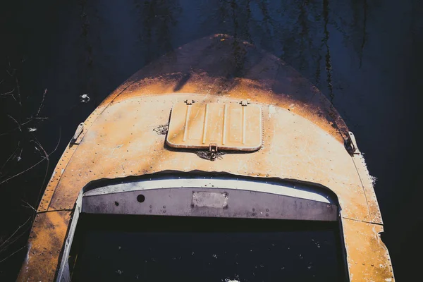 Sunken orange boat in dark river