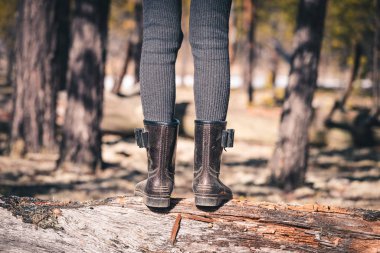 Lastik çizmeli ince bacaklar kamp gezisinde düşen ağaçların arasından geçiyor.