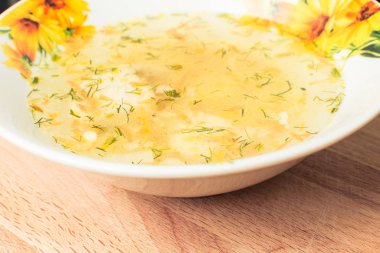 Tahtadaki kalın tabakta iştah açıcı tavuk çorbası.