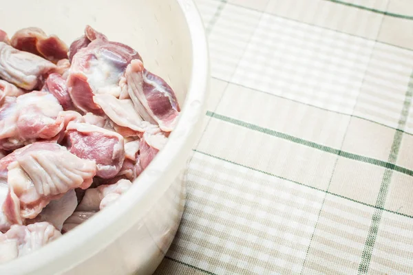 Thawed and washed chicken gizzards in eggplant on the kitchen table for cooking soup. — Stock Photo, Image