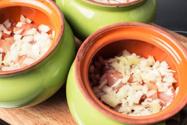 Fırında pişirmek için seramik kaba soğan serpiştirilmiş çiğ tavuk göğsü filetosu..