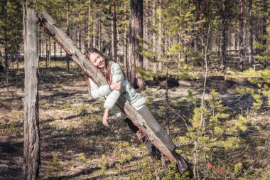 Uzun bir yürüyüşten sonra ceketli yorgun kız çam ormanındaki eski pürüzlerin üzerinde dinleniyor..