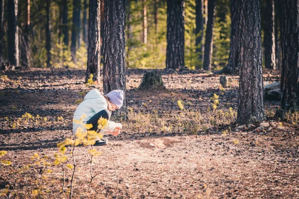 松林で砂遊びをするライトジャケットと帽子の大人の女の子. — ストック写真