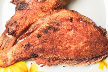 Mutfak masasında tabakta pişmiş kızarmış levrek.