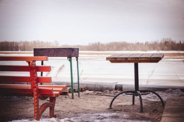 Masa, bank ve donmuş nehir kıyısında demir barbekü yapan turistler için dinlenme yeri.
