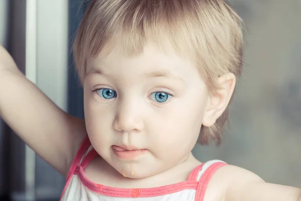 Menina loira com grandes olhos azuis se estende — Fotografia de Stock