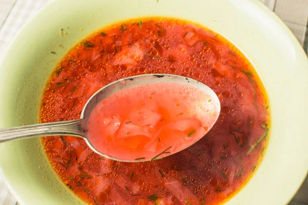 Red soup borsch with large spoon in green plate on kitchen table. — 스톡 사진