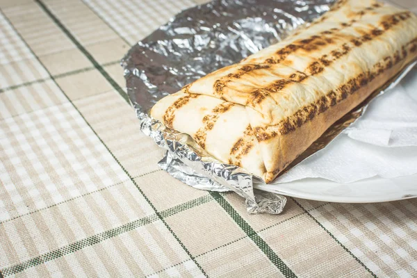 Daging segar dan shawarma sayuran dibungkus roti pita terletak di piring — Stok Foto