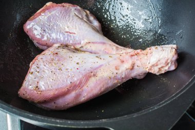 Fırında kızarmak için büyük bir kazanda tuz ve biber serpiştirilmiş çiğ hindi bacakları..