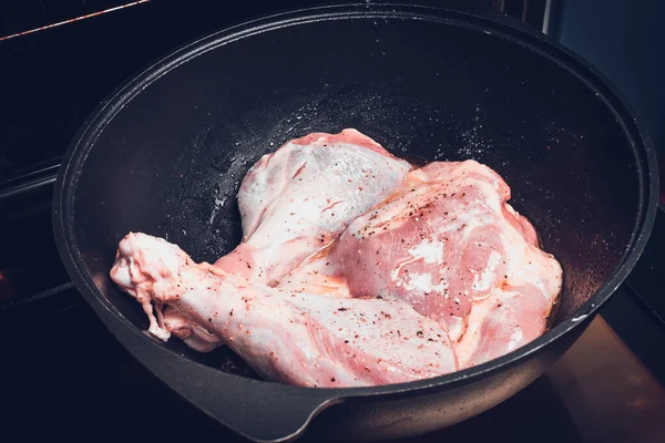 Delicate raw turkey legs sprinkled with salt and pepper in large cauldron for roasting in oven. — Stock Photo, Image