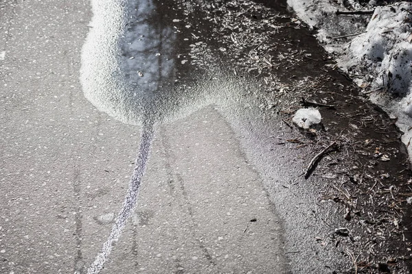Темная лужа с мокрыми следами, разбросанными по асфальту . — стоковое фото