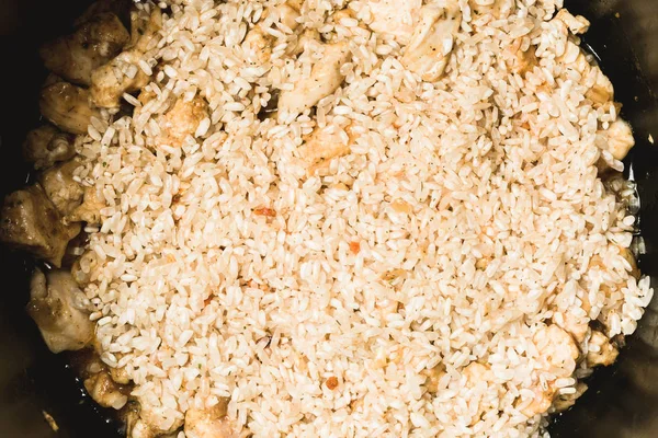 Laying ordinary rice and chicken pieces for making pilaf in slow cooker. — Stock Photo, Image