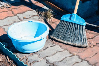 Baharda koyu mavi lavabo ile yeşillik ve çimenleri temizlemek ve temizlemek için sert kazık ile uzun süpürge