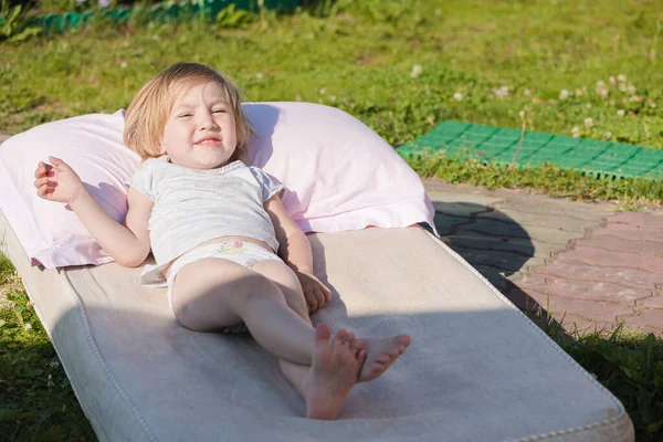 庭のマットレスの上に横たわっている間 太陽の下で小さな子供の日光浴 — ストック写真