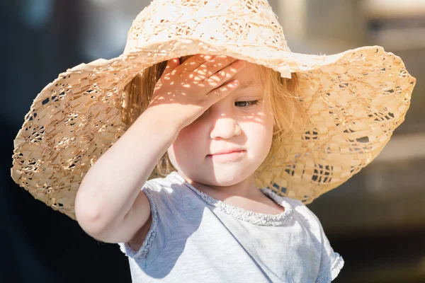 大きな帽子の小さな子供は燃え尽きることのないように太陽からカバーを取ります — ストック写真