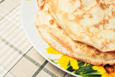 Kahvaltı için ince gözlemeler mutfak masasında büyük tabakta.