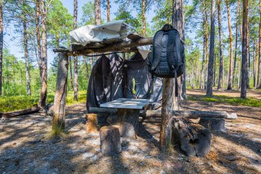 Siyah sırt çantası, ormanda dinlenmek için tahta kiriş çadırlarına asılır.