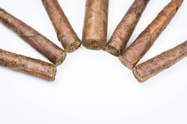 Beyaz arka planda tütün tabakalarından bükülmüş büyük ve küçük purolar.