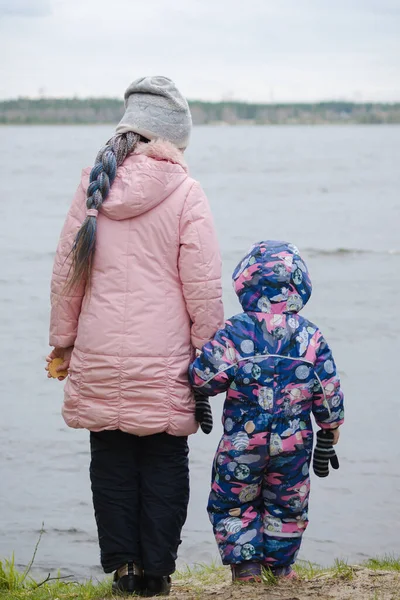 冬服の子供たちが湖の上に立っている — ストック写真