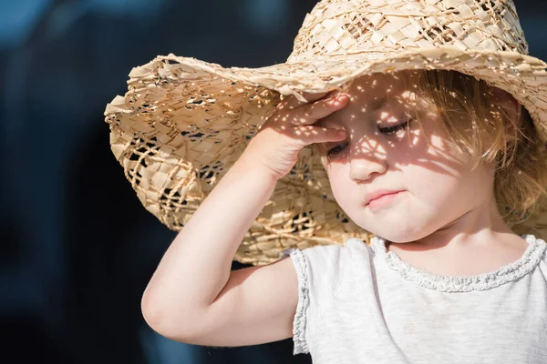 大きな帽子の小さな子供は燃え尽きることのないように太陽からカバーを取ります — ストック写真