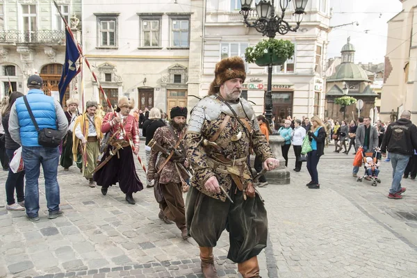 Personas vestidas como cosacos ucranianos cruzan la plaza Rynok en Lviv, Ucrania . — Foto de Stock