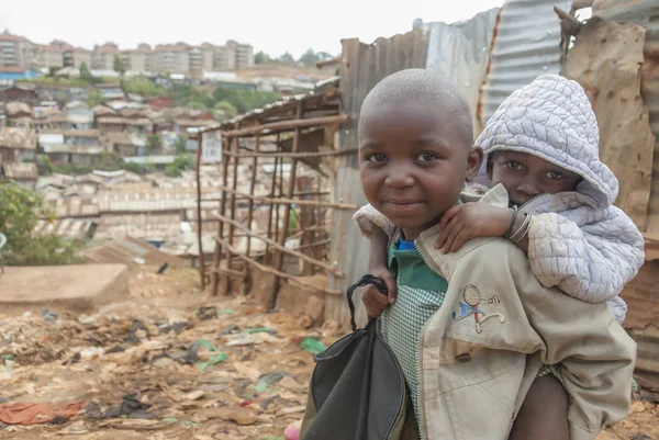 Chlapec s sebou nese jeho bratra na ulici v Kibera, Nairobi, Keňa. — Stock fotografie