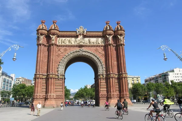 Emberek lovagolni kerékpárok keresztül az Arc de Triomf, Barcelona, Spanyolország. — Stock Fotó