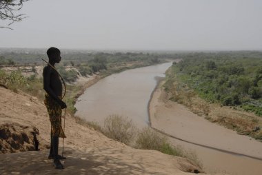 Vadi Omo, Etiyopya, 15 Mart 2012: Tanımlanamayan Karo çocuk pozlar onun yay üzerinde River Omo arka planda Colcho, Omo Vadisi, Etiyopya ile. Karo çocuklar kendilerine okulda eğitim yerine bakmak.