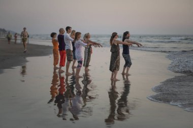 ARAMBOL, Hindistan, 9 Şubat 2020: Tanımlanamayan insanlar gün batımında Arambol plajında egzersiz yapıyorlar, Goa, Hindistan. Günbatımı insanların Goa, Hindistan 'da dinlenip meditasyon yaptığı geleneksel bir zamandır..