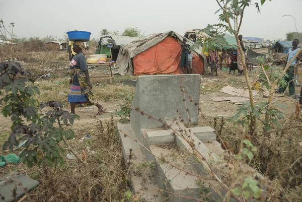 2012年2月28日 南スーダンのジュバ難民キャンプを背景に 未確認の女性が石の墓を通過した キャンプは放棄された墓地にあり 人々は厳しい状況にいます — ストック写真