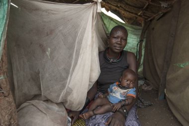 JUBA, SOUTH SUDAN, FEBRUARY 28, 2012: Bebekli kimliği belirsiz kadın, Juba, Güney Sudan 'daki yerlerinden edilmiş insanların kampında derme çatma bir kulübede oturuyor. Mülteciler Juba kamplarında zor koşullarda kalırlar..