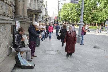 LVIV, UKRAINE, 7 Mayıs 2016: Lviv, Ukrayna 'da düzenlenen müzik festivalinde kimliği belirsiz yaşlı bir kadın sokak müzisyenlerini dinliyor. Lviv Ukrayna 'nın en önemli kültürel merkezlerinden biridir..