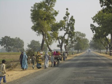 JHANSI DISTRICT, INDIA, HAZİRAN 13 Ocak 2007: Kimliği belirsiz insanlar Jhansi, Hindistan yakınlarındaki saha çalışmalarından sonra köylerine geri dönerler. Hindistan 'da hala kadınların ve çocukların el emeği kullanılıyor..       