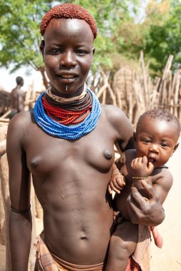 OMO VALLEY, ETHIOPIA, 17 Mart 2012: Colcho, Omo Vadisi, Etiyopya 'da kimliği belirsiz bir Karo kadının bebekli portresi. Karo kabilesi Omo Vadisi 'nin ötesindeki eşsiz yaşam tarzıyla ünlüdür..