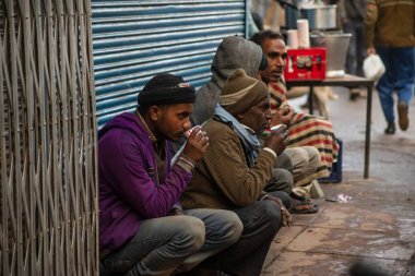DELHI, INDIA, JANUARY 29, 2020: Tanımlanamayan işçiler Delhi, Hindistan 'da çalışmaya başlamadan önce bir sokakta geleneksel süt çayı içiyorlar. Eski Delhi 'de yaşayanların çoğu hala gelişigüzel bir gelire bel bağlıyor..