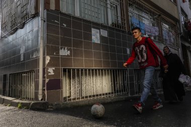 İstanbul, Türkiye 'de elinde futbol topu olan genç bir adam kentin Balat bölgesinde yürüyor.
