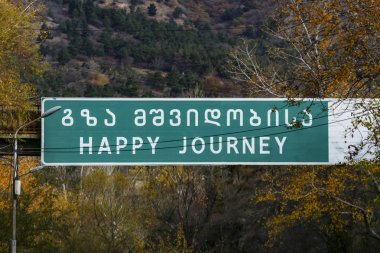 Tiflis, Gürcistan. Şehirden çıkan otoyolda Hjappy Seyahati yazan bir veda tabelası..