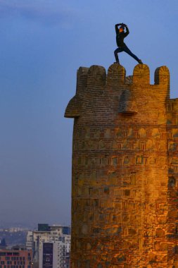 Tiflis, Gürcistan 'da bir adam tehlikeli bir şekilde eski kasabadaki Narikala Kalesi' nin tepesinde yoga hareketleri yapıyor..