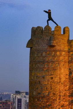 Tiflis, Gürcistan 'da bir adam tehlikeli bir şekilde eski kasabadaki Narikala Kalesi' nin tepesinde yoga hareketleri yapıyor..