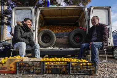 Tiflis, Gürcistan. İki adam kamyonetlerinin arkasında mandalina satıyor. İstasyon Meydanı 'ndaki yoğun meyve ve sebze pazarında..