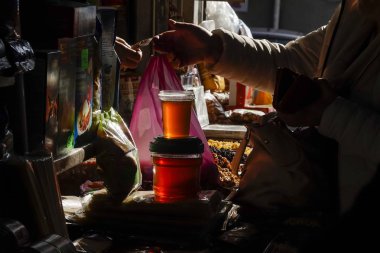 Tiflis, Gürcistan. İstasyon Meydanı 'ndaki işlek meyve ve sebze pazarında bal yiyen bir kadın..