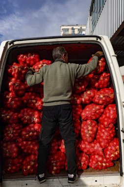 Tiflis, Gürcistan 'da bir adam İstasyon Meydanı' ndaki işlek meyve ve sebze pazarında torba dolusu soğan satıyor..