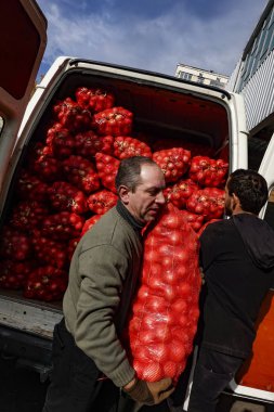 Tiflis, Gürcistan 'da bir adam İstasyon Meydanı' ndaki işlek meyve ve sebze pazarında torba dolusu soğan satıyor..