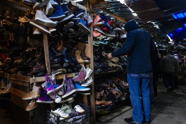 Tiflis, Gürcistan. İstasyon Meydanı 'ndaki kalabalık pazarda yüzlerce çift ayakkabıya göz atan bir adam..
