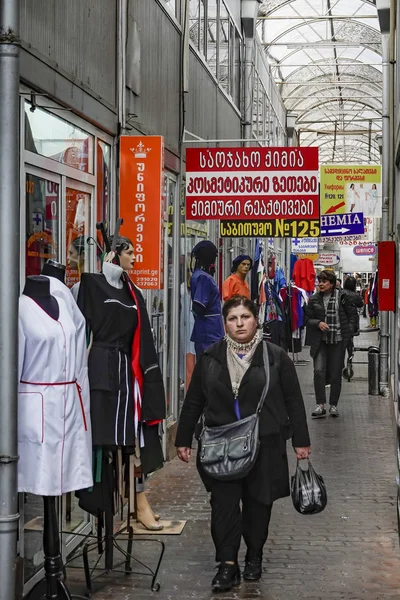 格鲁吉亚第比利斯一名妇女在一个带有格鲁吉亚标志的小购物中心中行走 — 图库照片