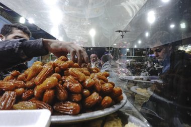 Siwa Oasis, Egypt, A street vendor plucking Tulumba or Bamiyeh is a deep-fried dessert. It is a fried batter soaked in syrup.