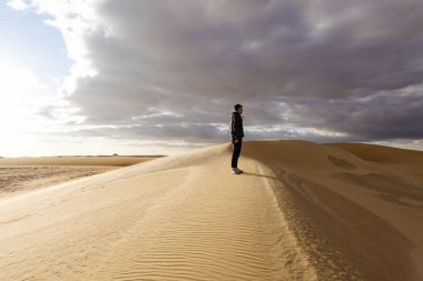 Siwa vahası, Mısır. Bir adam vaha dışındaki kum tepelerinde yürüyor..