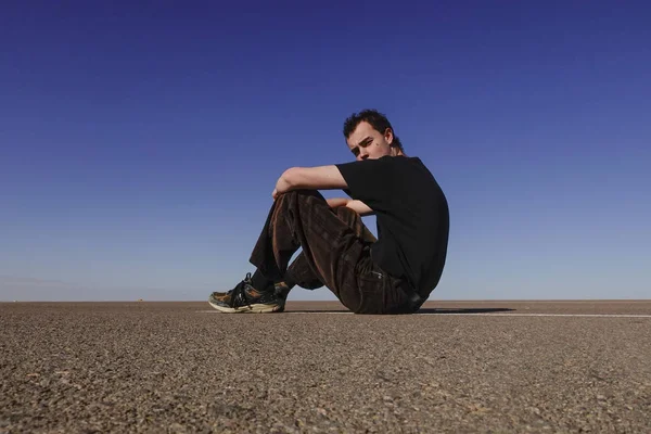 エジプトのマルサ マトゥルー若い男がサハラ砂漠の空の道に座っている — ストック写真